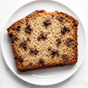 Mixing chocolate chips and mashed bananas into banana bread batter, creating a thick, moist texture.