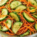 Crunchy cucumber carrot salad with bright orange carrot ribbons and crisp green cucumber slices, drizzled with vinaigrette