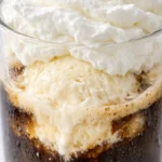 Rich iced coffee float with creamy vanilla ice cream, dark cold brew, and whipped cream in a tall glass