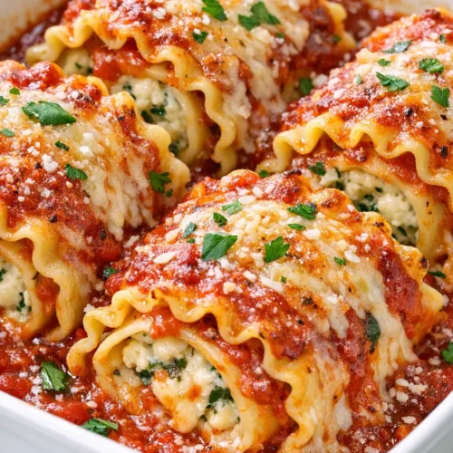 Golden brown lasagna roll-ups topped with marinara sauce and melted mozzarella cheese, garnished with fresh basil.