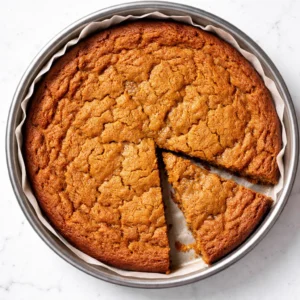 Dark browned butter poured over pumpkin puree and sugar, creating a glossy spiced batter for brown butter pumpkin cookie cake.