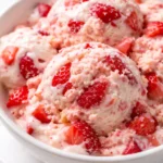 Creamy strawberry shortcake ice cream with fresh strawberries and golden shortcake crumbles, topped with whipped cream.