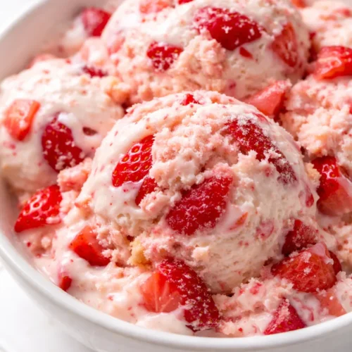 Creamy strawberry shortcake ice cream with fresh strawberries and golden shortcake crumbles, topped with whipped cream.