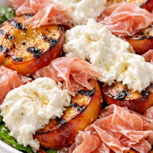 Grilled nectarine burrata prosciutto salad with golden nectarines, creamy burrata, and crispy prosciutto on arugula.