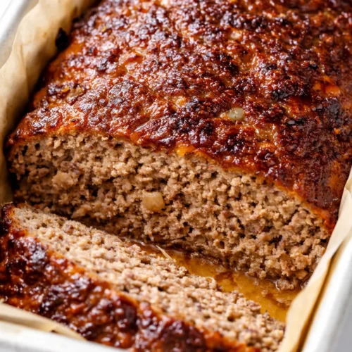 Moist Lipton onion soup meatloaf sliced on a plate with rich brown glaze and tender texture.