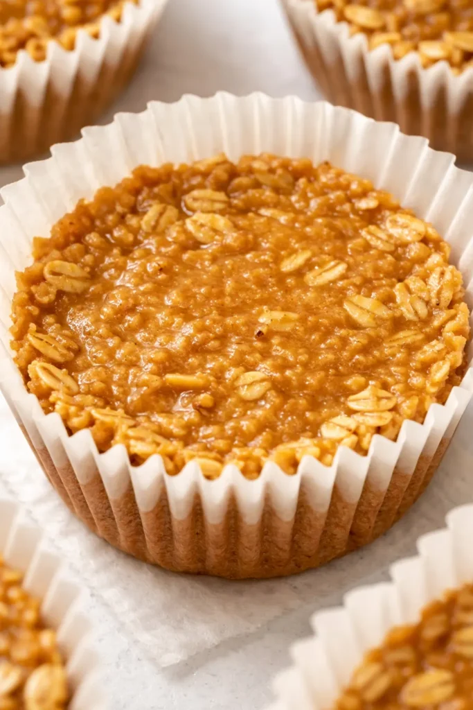 Stacked no-bake peanut butter oat cups with a glossy peanut butter drizzle, showing a chewy texture and specks of oats.