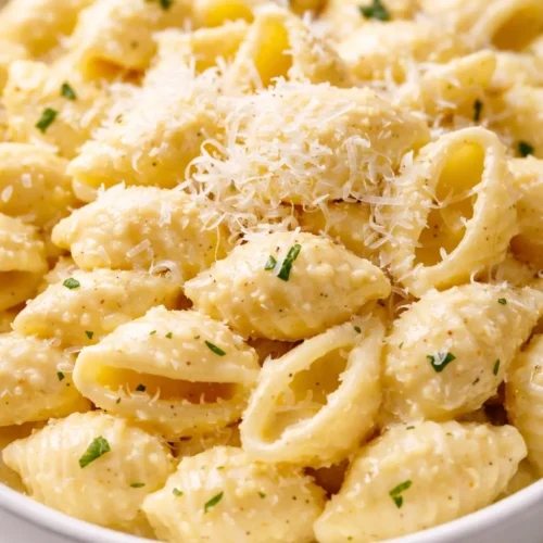 Creamy lemon ricotta pasta with fresh lemon zest and parsley in a white ceramic bowl, garnished with a fork.