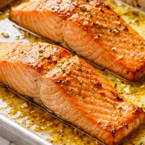 Sheet pan lemon garlic butter salmon with roasted lemon slices and fresh parsley, featuring crispy golden skin and flaky tender flesh.