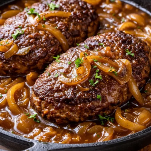 Rich and tender Amish hamburger steak smothered in savory brown gravy, served with mashed potatoes and green beans.