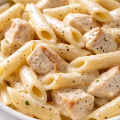 Creamy chicken penne pasta coated in a rich white sauce with tender chicken pieces and fresh parsley garnish.
