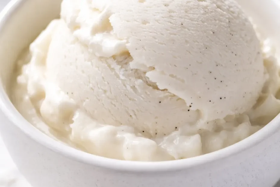 Scoop of creamy coconut ice cream with a smooth, velvety texture and pale white color in a glass bowl.