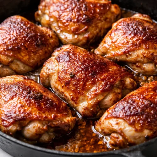 Crispy golden chicken thighs with bell peppers and onions in a glossy one-pan braise, garnished with fresh parsley.