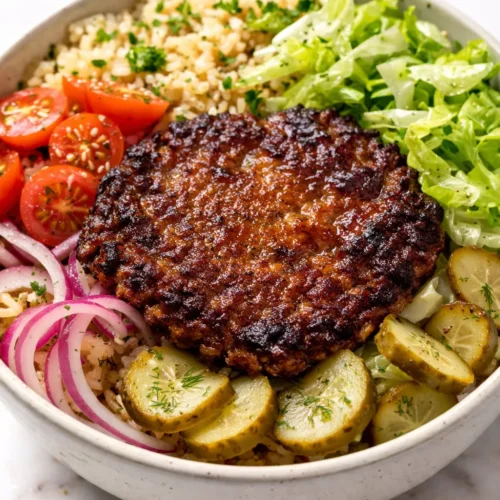 Smashed beef patties with melted cheddar, crispy edges, and fresh lettuce, tomato, and pickles in a bowl, juicy smash burger bowl.