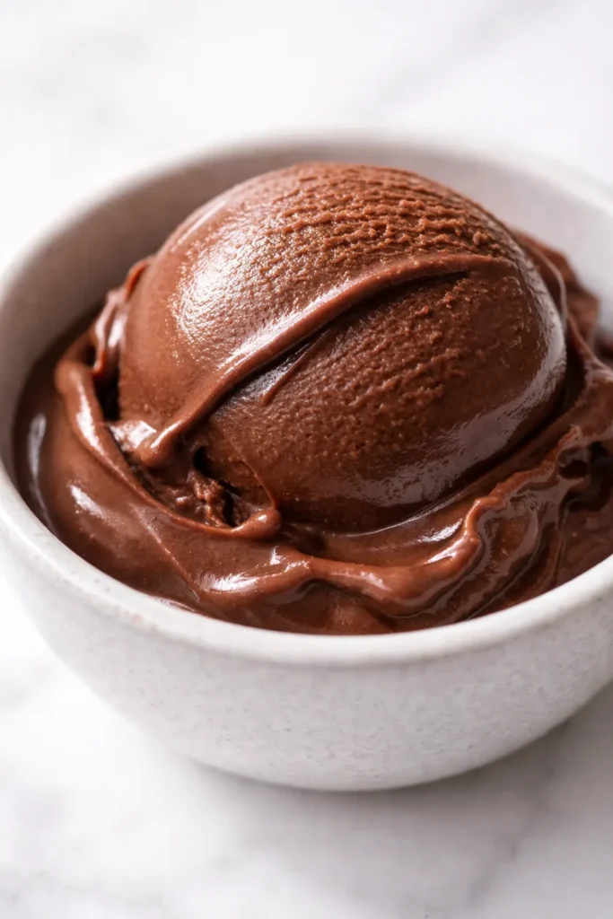Smooth, dangerously dark chocolate gelato with a silky, slow-melt texture and glossy surface in a glass bowl.