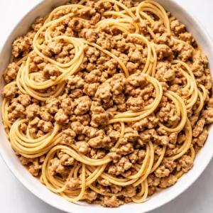 Ground turkey browning in a skillet with garlic and herbs, getting golden and fragrant for Gordon Ramsay's pasta recipe.