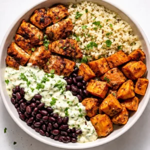 Layering black beans, grilled chicken, and quinoa in a meal prep container for high protein freezer friendly bowls.