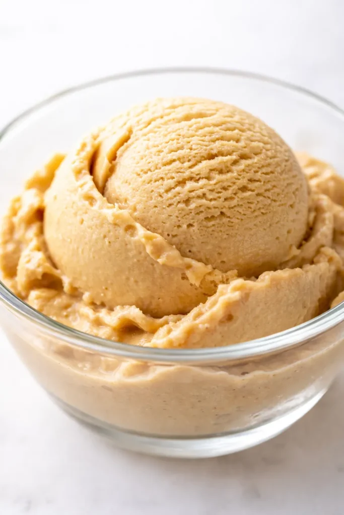 Scoop of creamy homemade coffee ice cream with rich brown color and smooth texture in a chilled glass bowl.