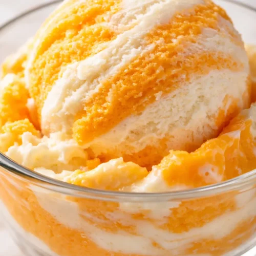 Creamy homemade orange creamsicle ice cream scoop with white vanilla and orange swirls, smooth texture with no ice crystals.