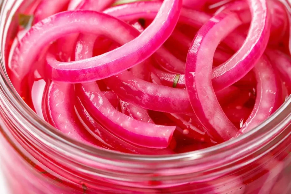 Vibrant magenta pickled red onion slices in a glass jar, crisp and glossy, showcasing their crunchy texture after a quick 15-minute prep.