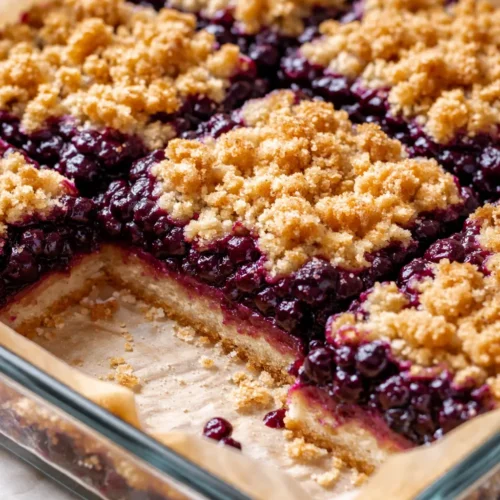 Golden huckleberry crumb bars with buttery oat topping and bright purple filling, fresh from the oven.