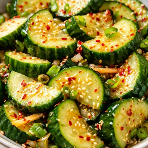 Crisp Korean cucumber salad with spicy gochugaru dressing, sesame seeds, and green onions, glossy and vibrant.