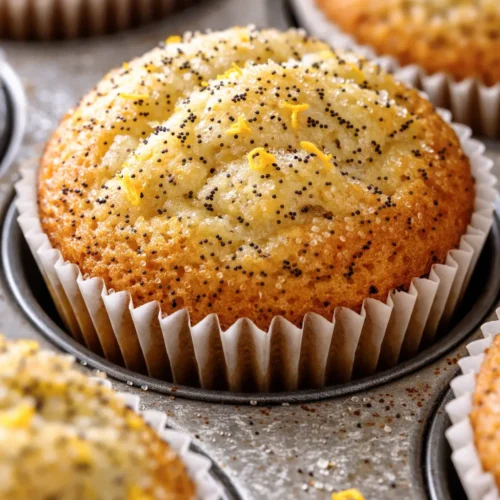 Golden brown tender lemon poppy seed muffins with a bright citrus glaze, dotted with poppy seeds, on a rustic wooden board.