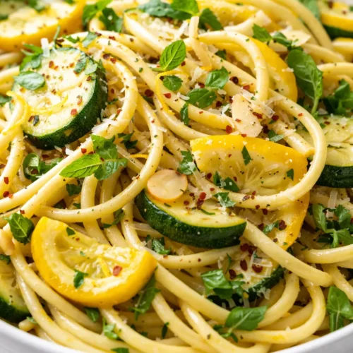 Light summer squash pasta with creamy sauce and tender ribbons of zucchini and yellow squash, topped with fresh basil and Parmesan.