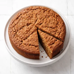 Mixing smooth white batter with crumbled Lotus Biscoff cookies in a single bowl, caramel swirls blending in