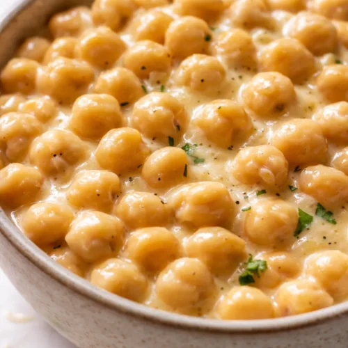 Creamy marry me chickpeas in a rich, golden sauce, garnished with fresh parsley and red pepper flakes, served in a white bowl.