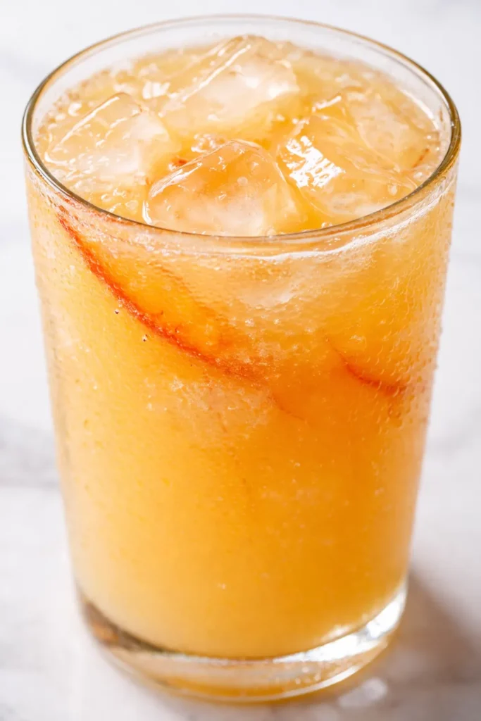Golden peach lemonade with ice and fresh peach slices, a refreshing summer drink perfect for hot days.