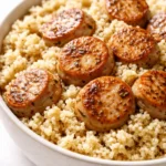 Quinoa chicken sausage bowl with tender quinoa, sliced savory sausage, roasted vegetables, and fresh herbs in a rustic bowl