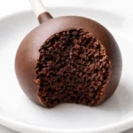 Golden brown cake pop coated in pink strawberry coating with rainbow sprinkles, resembling Starbucks cake pop.