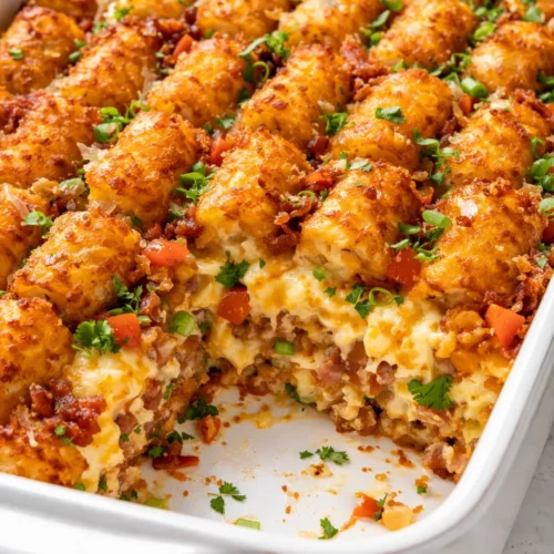 Tater tot breakfast casserole with crispy golden top and creamy custardy center, served in a baking dish.