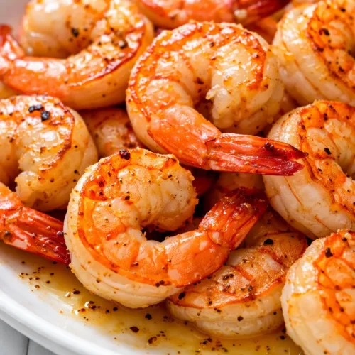 Crispy air fryer garlic parmesan shrimp with golden brown crust, juicy interior, and parsley garnish on a white plate.