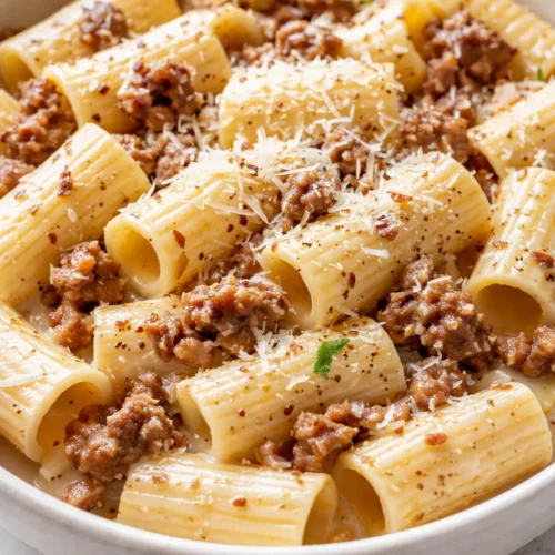 Creamy rigatoni with Italian sausage in a rich tomato cream sauce, topped with Parmesan and fresh basil.