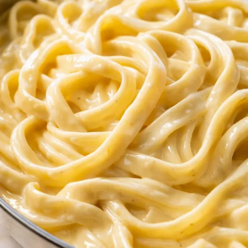 Creamy homemade alfredo sauce tossed with fettuccine pasta, topped with chopped parsley and cracked black pepper.