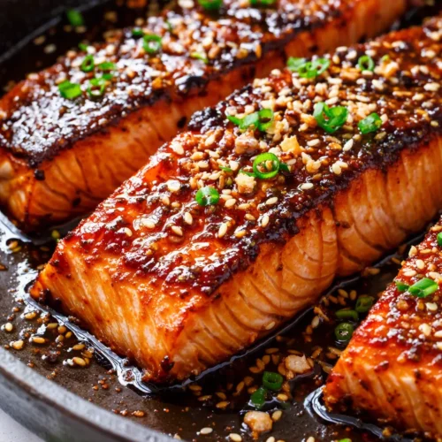 Sticky honey garlic soy glazed salmon fillet with glossy caramelized glaze, garnished with sesame seeds and green onions
