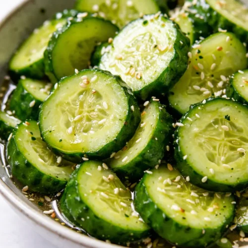 Vibrant Japanese cucumber salad with thin slices in a tangy dressing, garnished with sesame seeds, showcasing a crisp, non-watery texture.