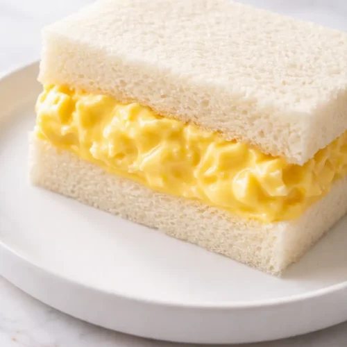 Japanese egg sandwich with soft creamy egg salad filling on milk bread, golden crust, fluffy texture
