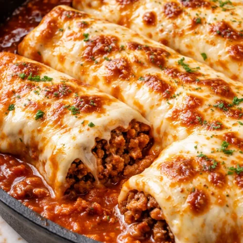 Smothered ground beef burritos topped with melted cheese, red sauce, and cilantro on a plate.