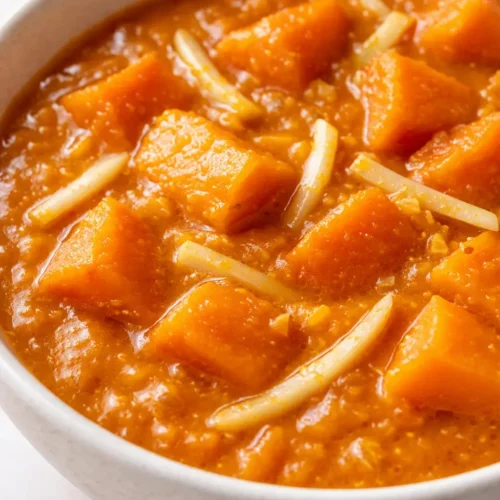 Sämiges Kürbis Curry mit Ingwer in leuchtend orangener Farbe, garniert mit frischem Koriander und Kokosmilch.